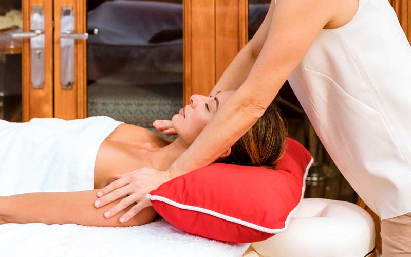 Woman in towel laying on a massage table, face up, while getting a massage on NERO Yacht.