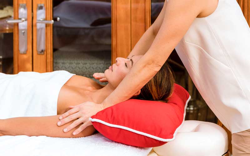 Woman in towel laying on a massage table, face up, while getting a massage on NERO Yacht.