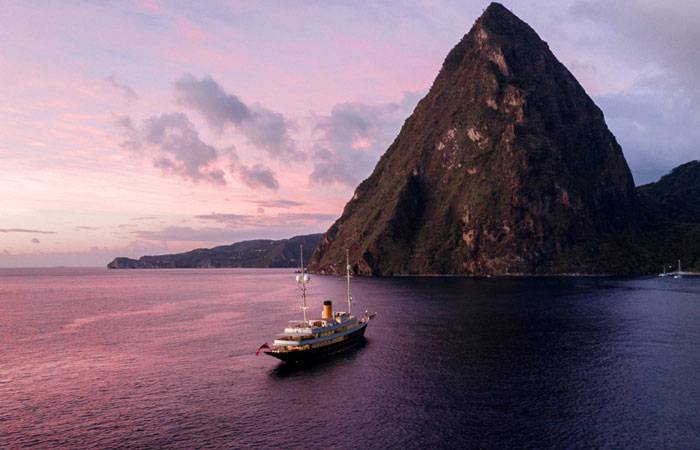 Aerial view of NERO Yacht off the coast of a mountainous shoreline.