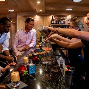 Two men being served drinks by bartenders on NERO Yacht.