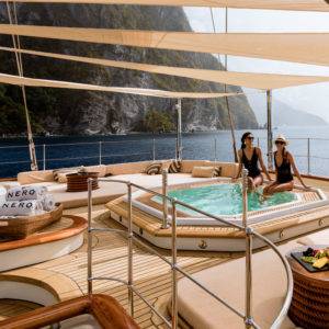 Two women sitting in a Jacuzzi under shade on NERO Yacht.