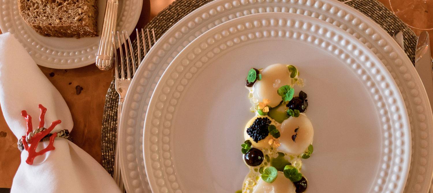 Table setting with piece of bread on a plate and another plate with gourmet cuisine from NERO's chef.