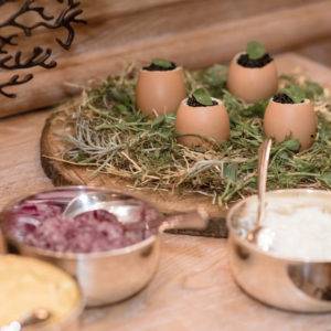 Egg shells with filling on a wooden plate garnished with herbs.