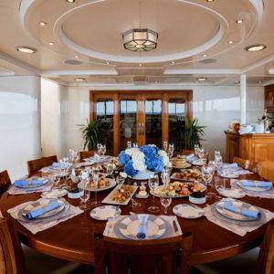 Formally set table with blue and white flowers and various foods on NERO Yacht.